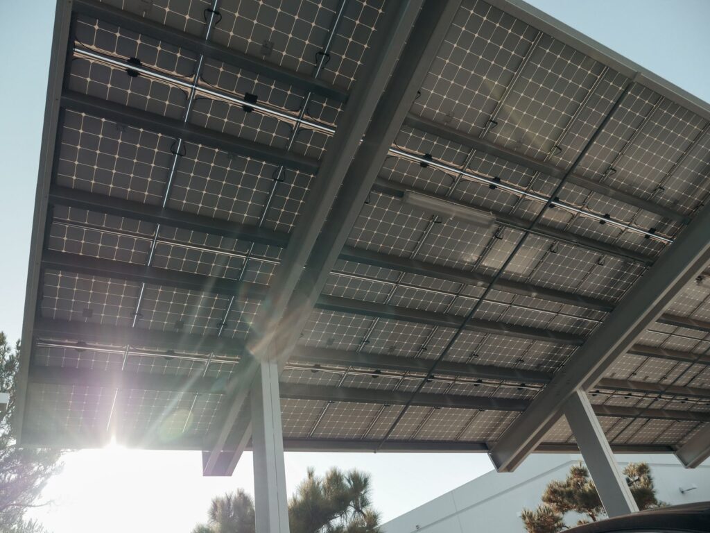 Solar Pergolas for Your Backyard: 2026 Power & Shade Guide 2 metal pergola carport with solar panels over a driveway