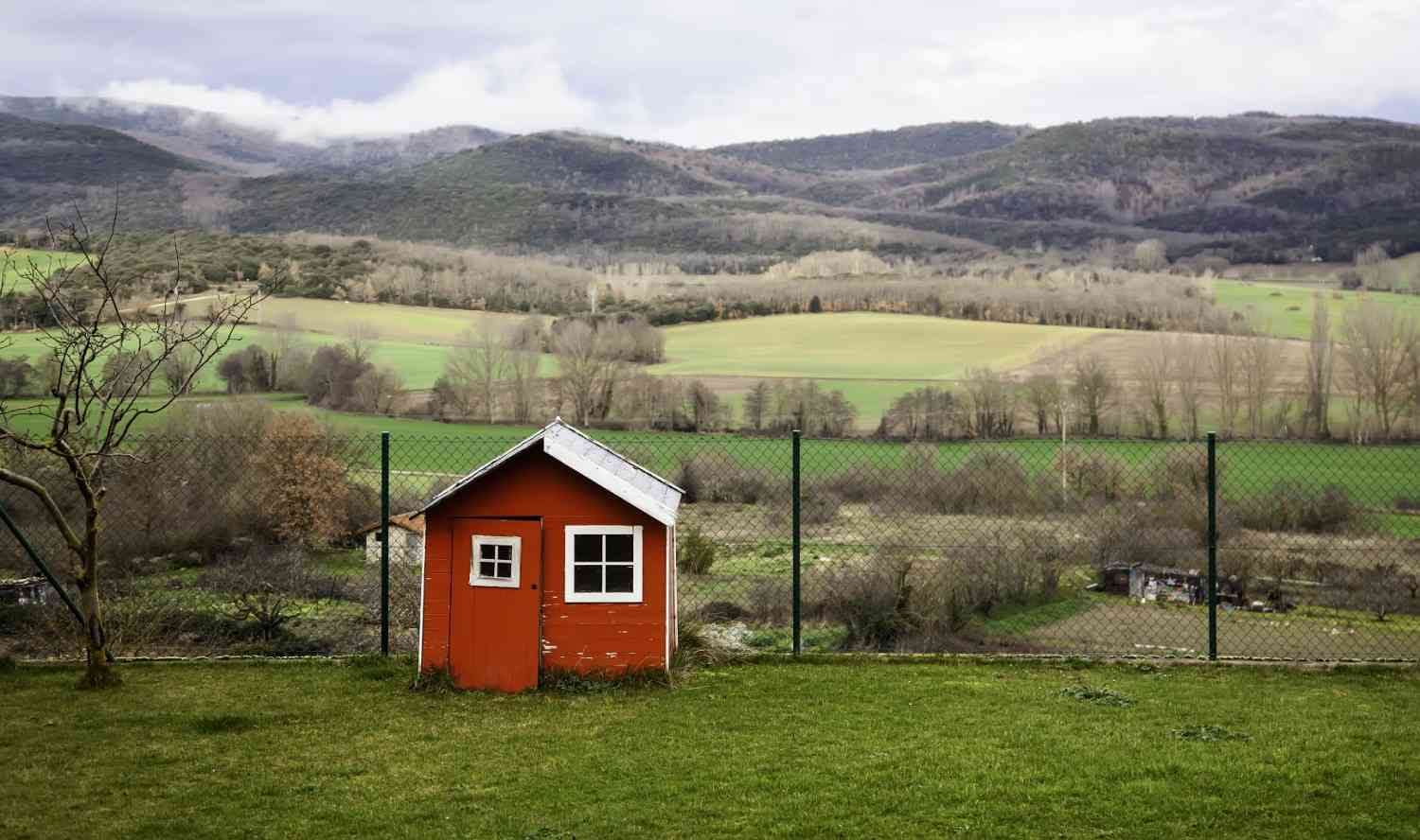Small red house in green landscape.
