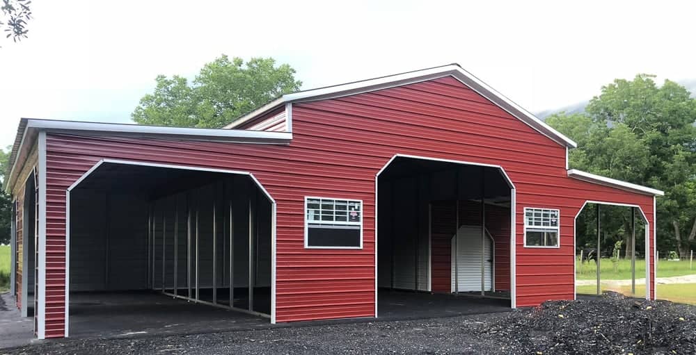 Red custom metal barn building with white trim, open lean-to side bays, main drive-through opening, framed windows, and steel framing on an asphalt lot in Brooksville, FL.