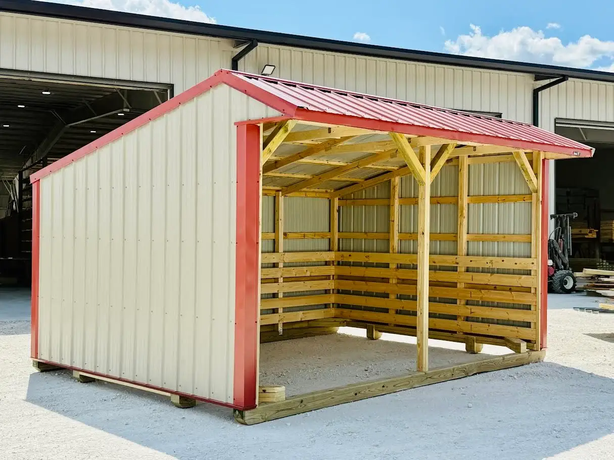 Beige and red custom metal loafing shed with an open front design, heavy-duty timber interior framing, and kickboards on a gravel lot in Brooksville, FL.