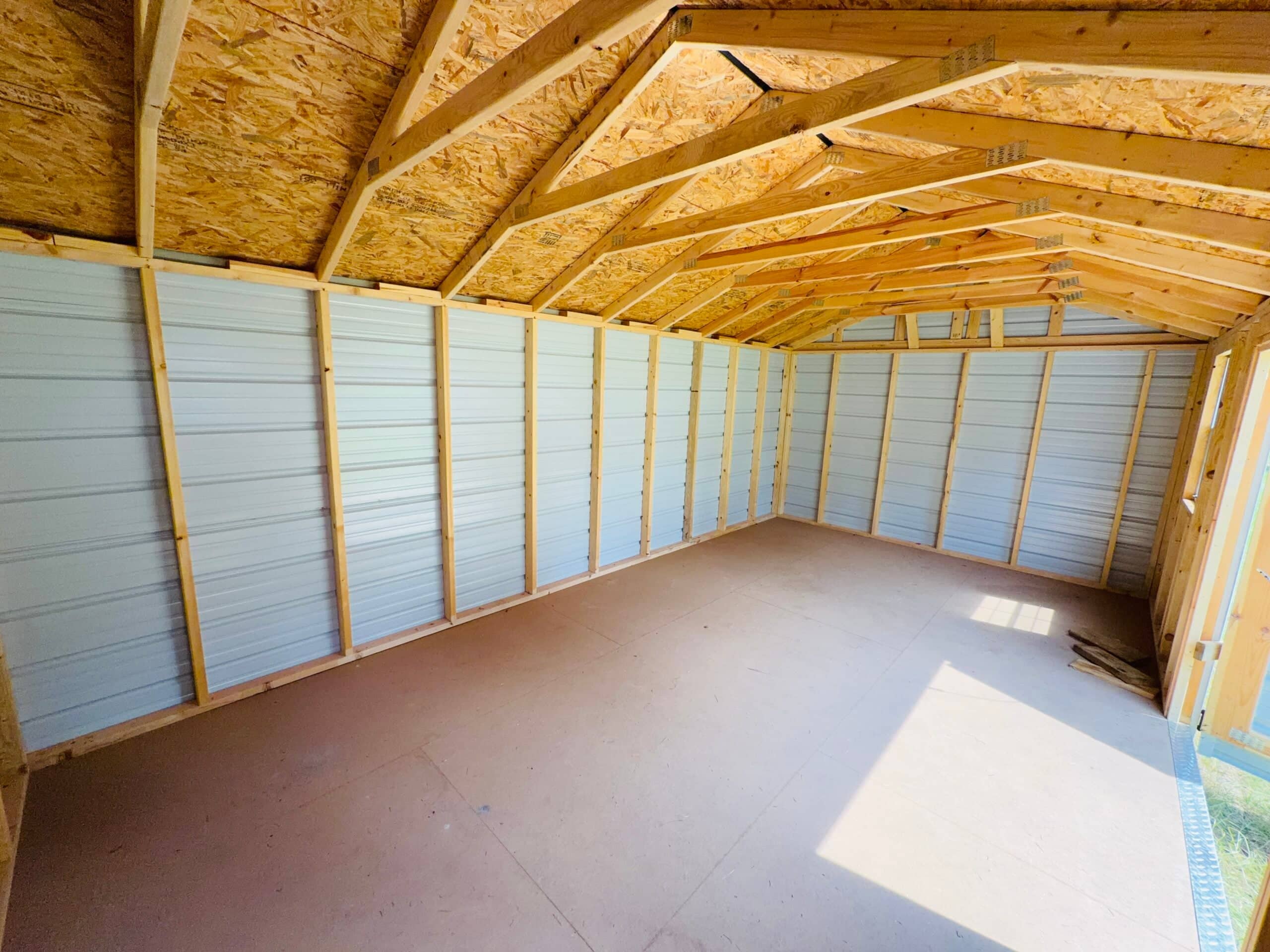 Spacious interior view of an unfinished metal storage shed with wooden framing and roof trusses in The Villages, FL.