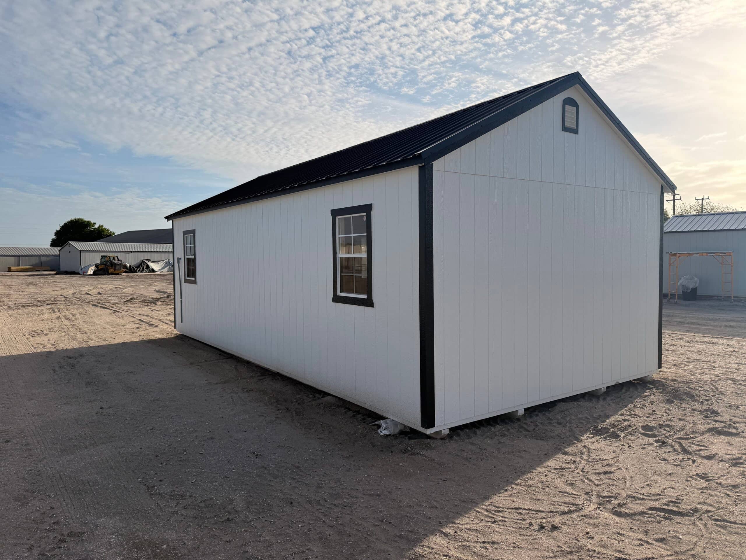 White storage shed on sandy ground