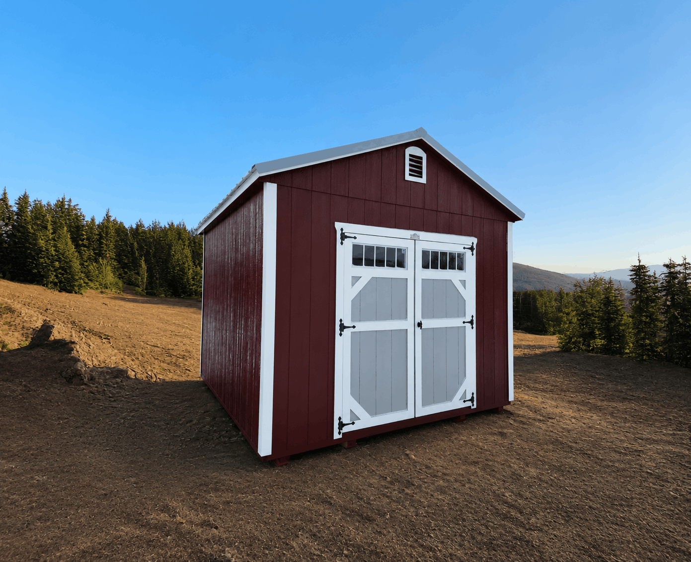 Deep red wooden utility storage shed with white double doors, light grey door accents, dark trim, and a gable vent against a scenic mountain backdrop in Wildwood, FL.